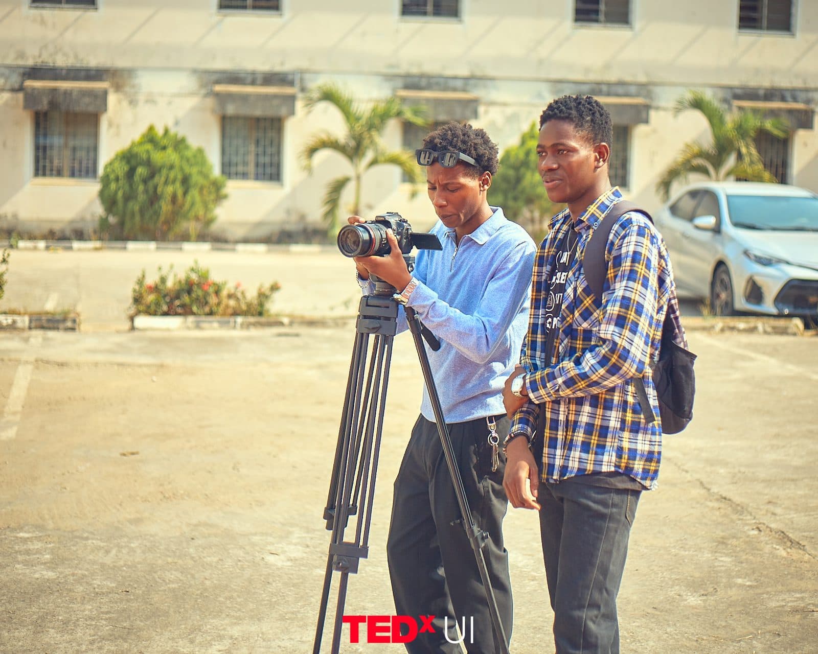 The media crew filming outside the venue with a tripod-mounted camera.